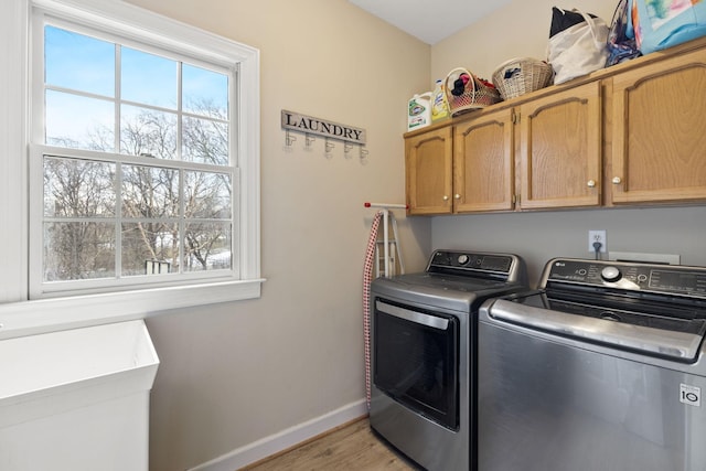 laundry area featuring light hardwood / wood-style floors, separate washer and dryer, and cabinets