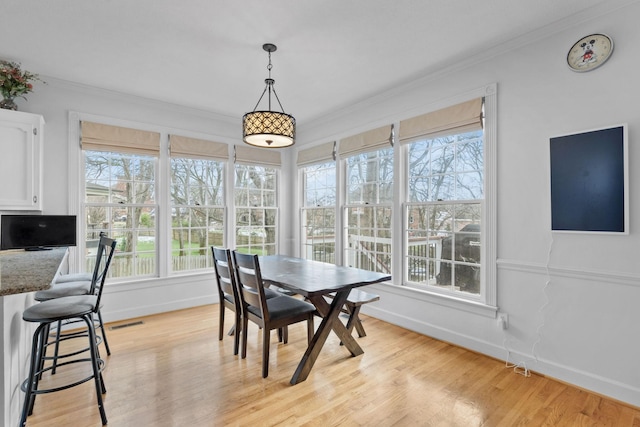 dining space featuring light wood-type flooring and ornamental molding