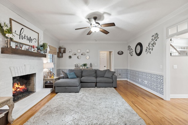 living room with hardwood / wood-style flooring, ceiling fan, ornamental molding, and a fireplace