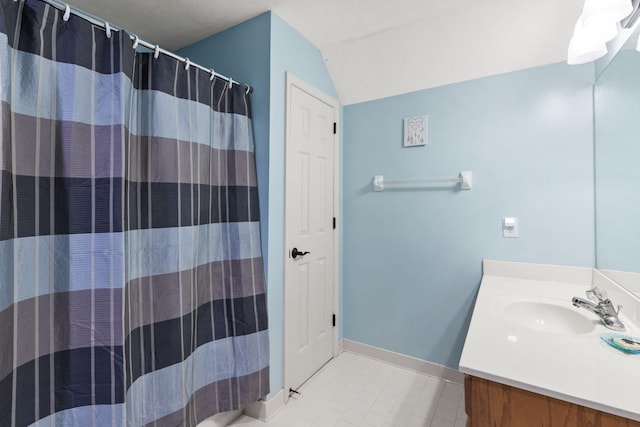 bathroom featuring a textured ceiling, walk in shower, lofted ceiling, and vanity