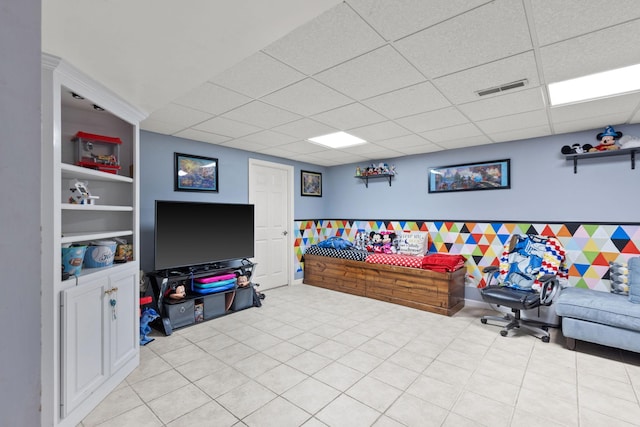 recreation room featuring built in features and a drop ceiling