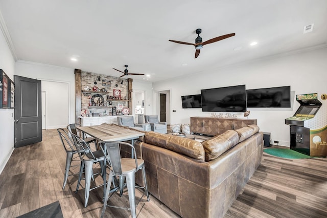 living room featuring wood-type flooring, ornamental molding, and indoor bar