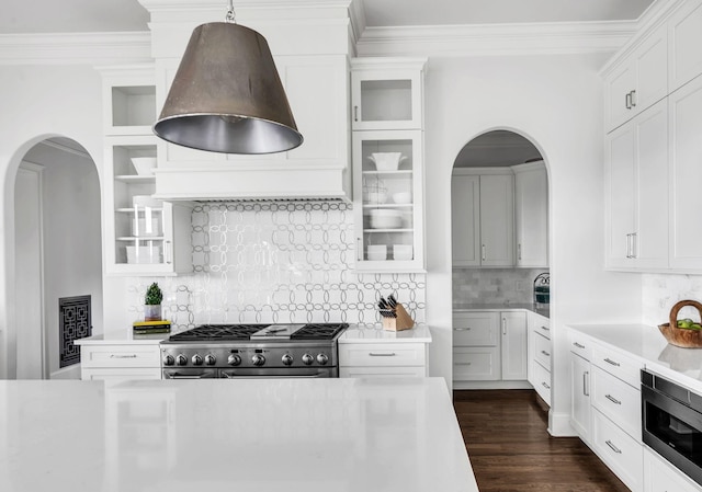 kitchen with white cabinetry, built in microwave, high end stainless steel range oven, tasteful backsplash, and decorative light fixtures