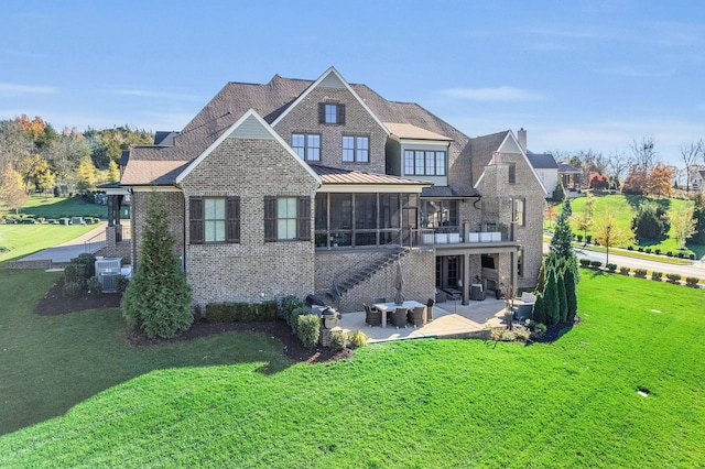 rear view of house with a lawn, a sunroom, and a patio