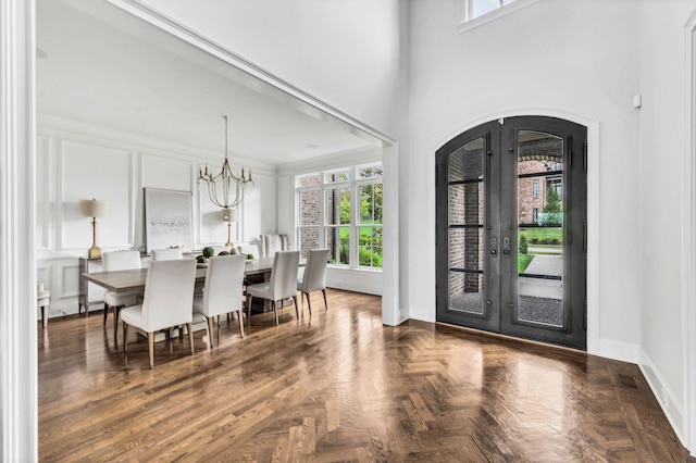 foyer featuring french doors, dark parquet floors, a chandelier, and ornamental molding