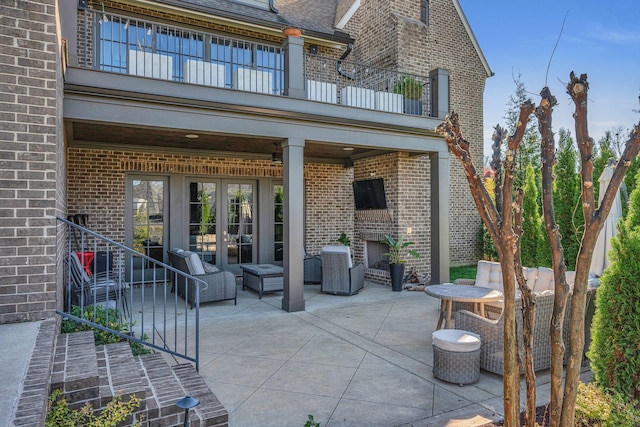 view of patio with french doors, a balcony, and an outdoor brick fireplace