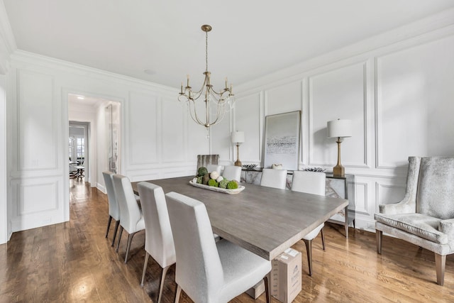 dining space featuring hardwood / wood-style flooring, ornamental molding, and a notable chandelier