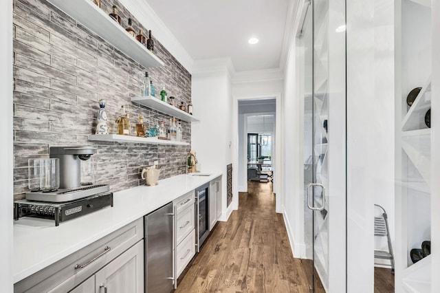 bar with sink, beverage cooler, crown molding, hardwood / wood-style floors, and fridge