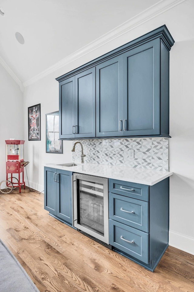 bar featuring decorative backsplash, ornamental molding, blue cabinetry, and beverage cooler