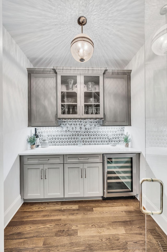 bar with backsplash, dark wood-type flooring, wine cooler, and gray cabinetry