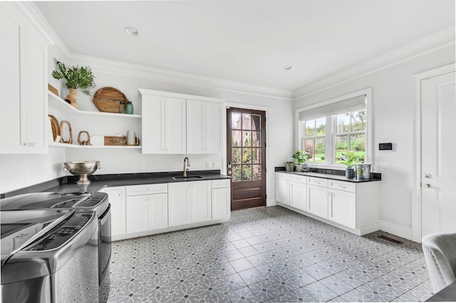 kitchen featuring stove, crown molding, sink, white cabinets, and independent washer and dryer