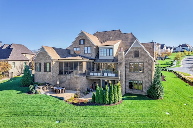 back of house featuring a yard, a patio, and a sunroom