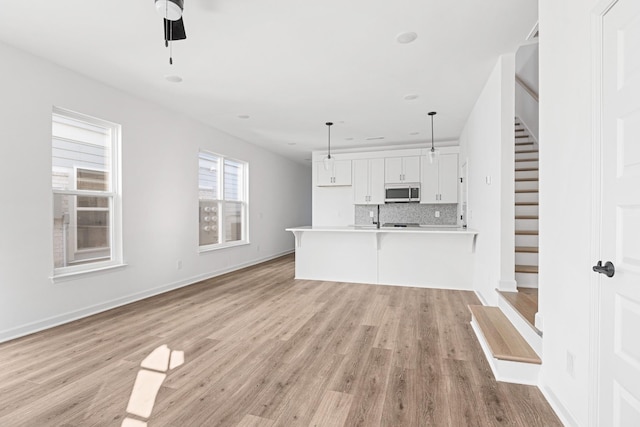 unfurnished living room with ceiling fan and light wood-type flooring