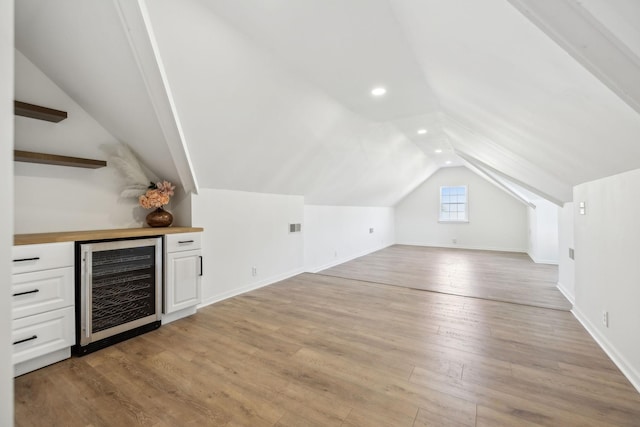 bonus room with lofted ceiling, wine cooler, light hardwood / wood-style flooring, and bar area