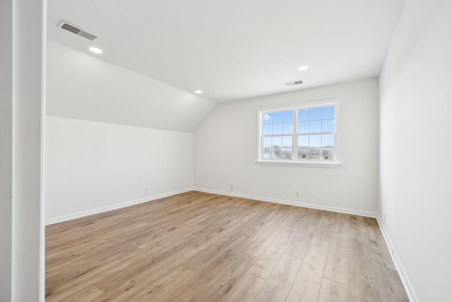 additional living space featuring vaulted ceiling and light wood-type flooring