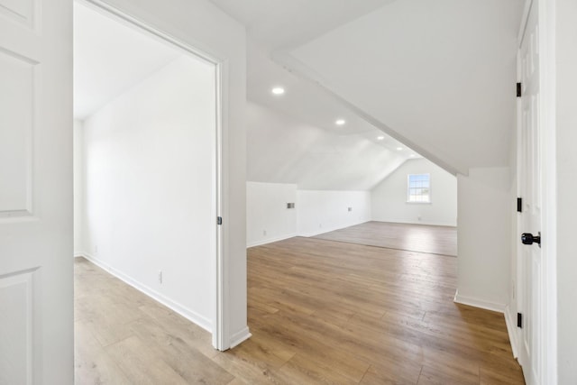 additional living space with light wood-type flooring and vaulted ceiling