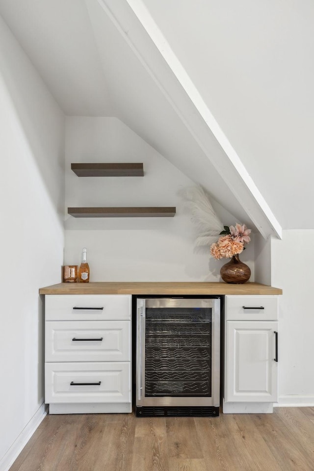 bar with white cabinetry, wine cooler, light hardwood / wood-style flooring, and wooden counters