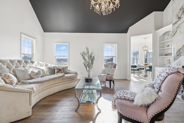 living room with hardwood / wood-style floors, built in features, a wealth of natural light, and a chandelier