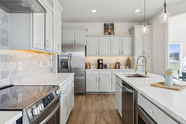 kitchen featuring premium range hood, appliances with stainless steel finishes, light stone countertops, pendant lighting, and sink