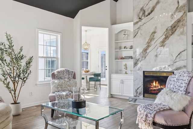 living room with built in features, a premium fireplace, and light hardwood / wood-style flooring