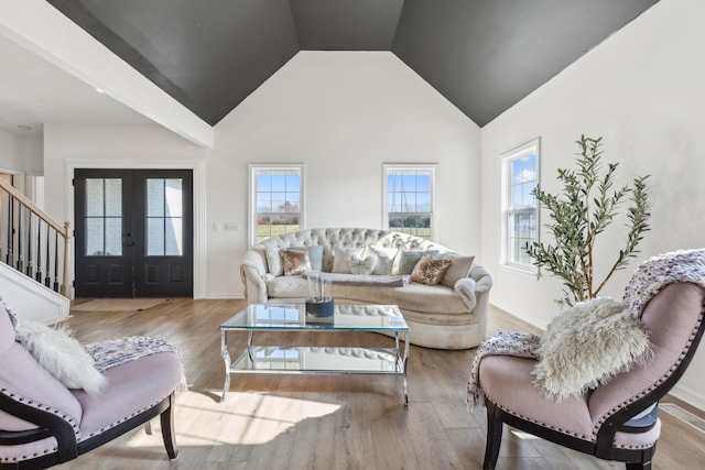 living room with high vaulted ceiling, french doors, and light wood-type flooring