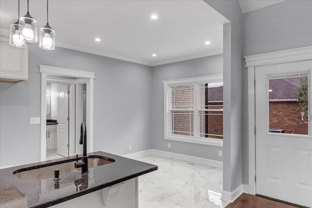 kitchen with an inviting chandelier, crown molding, hanging light fixtures, dark stone countertops, and white cabinetry