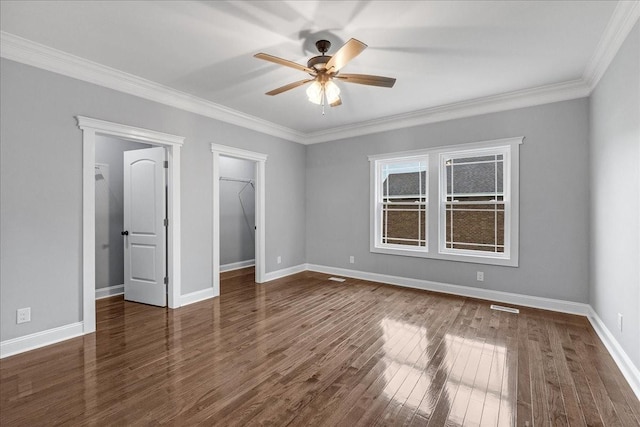 unfurnished bedroom with a walk in closet, crown molding, ceiling fan, dark hardwood / wood-style flooring, and a closet