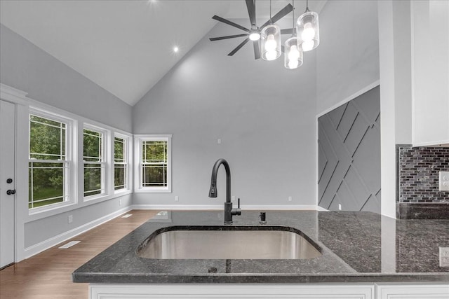 kitchen featuring plenty of natural light, dark stone countertops, white cabinetry, and sink