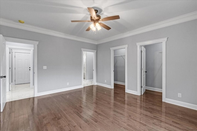 unfurnished bedroom with hardwood / wood-style flooring, ceiling fan, a walk in closet, and crown molding