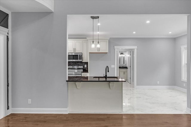 kitchen with a kitchen breakfast bar, sink, hanging light fixtures, crown molding, and stainless steel appliances