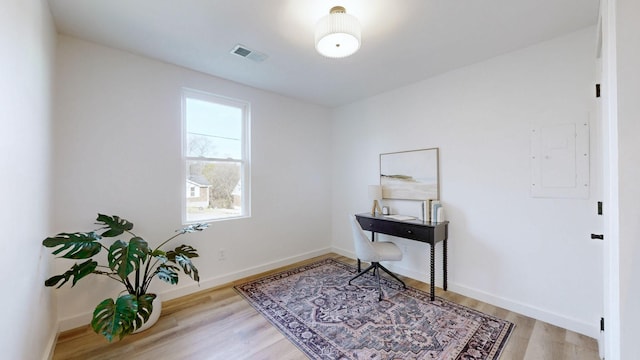 home office featuring electric panel and light hardwood / wood-style flooring