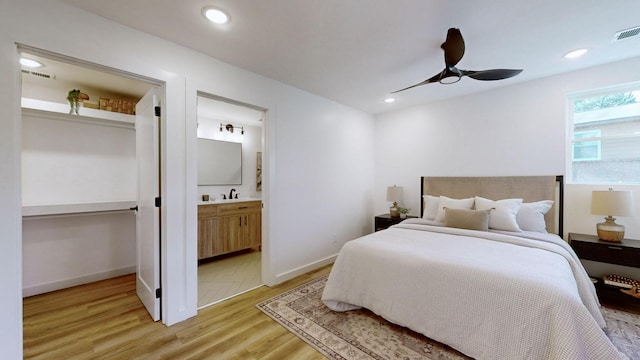 bedroom featuring light hardwood / wood-style floors, ensuite bath, ceiling fan, and sink