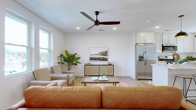 living room featuring light wood-type flooring and ceiling fan