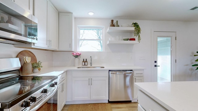 kitchen featuring white cabinets, sink, light hardwood / wood-style flooring, tasteful backsplash, and stainless steel appliances