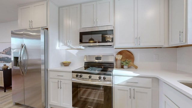 kitchen with white cabinets, stainless steel appliances, and light hardwood / wood-style floors