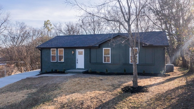 ranch-style house with central air condition unit and a front yard