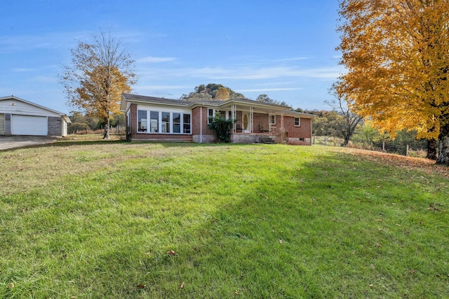 ranch-style home featuring a garage, a front lawn, an outdoor structure, and covered porch