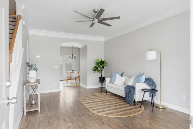 living area featuring ceiling fan with notable chandelier, dark wood-type flooring, and crown molding