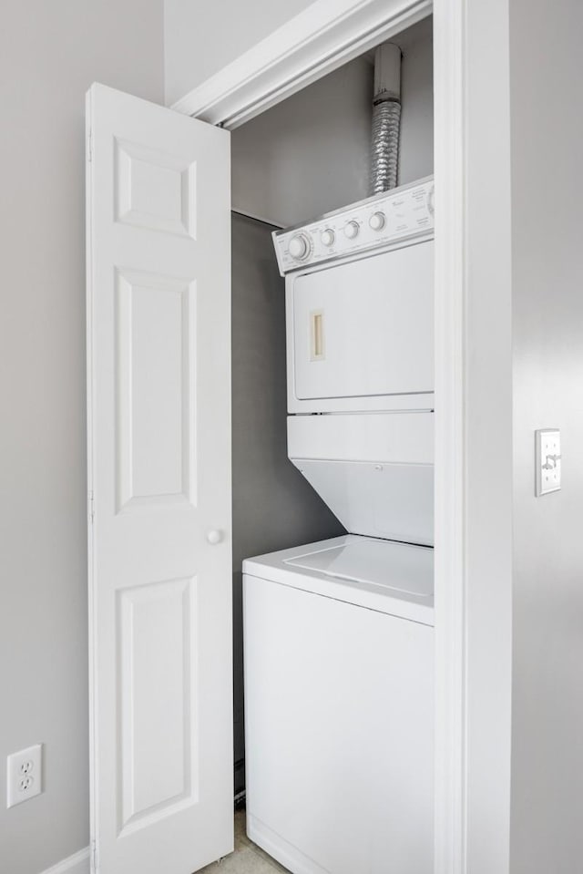 clothes washing area featuring stacked washer and clothes dryer