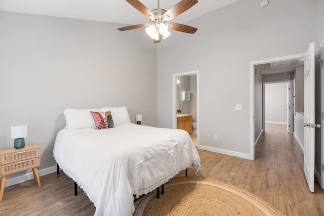 bedroom featuring ensuite bath, ceiling fan, light hardwood / wood-style floors, and a high ceiling