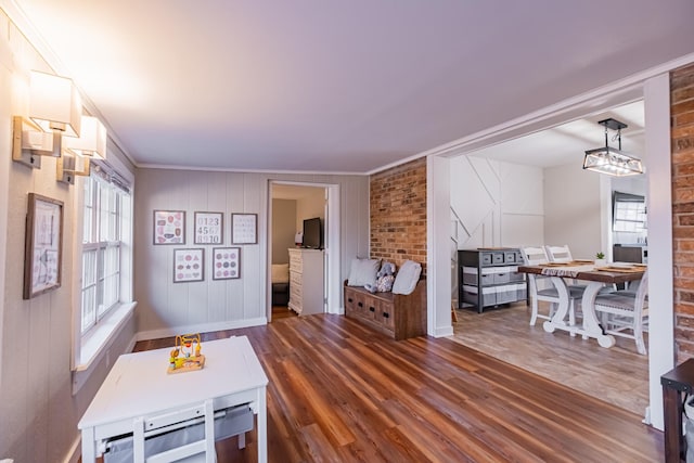 dining space featuring crown molding, wooden walls, dark wood-type flooring, and brick wall