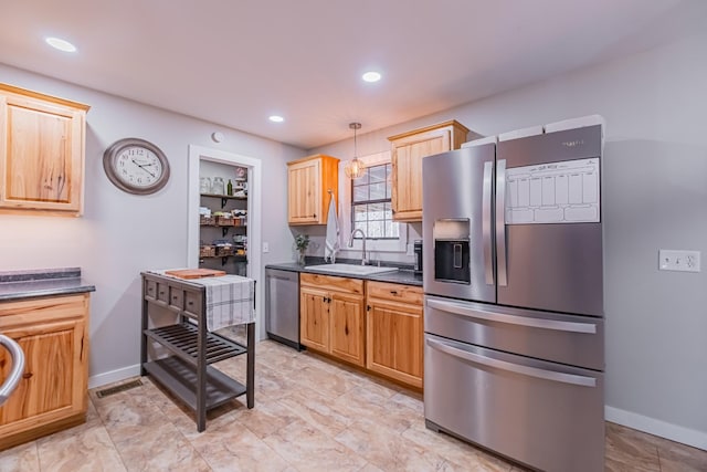 kitchen featuring sink, light brown cabinets, built in features, decorative light fixtures, and appliances with stainless steel finishes