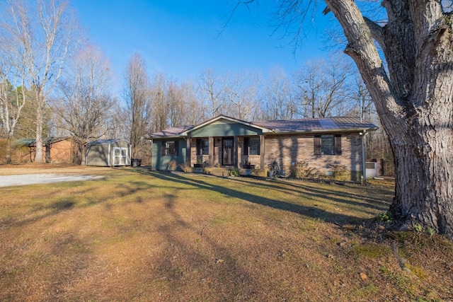 ranch-style house with solar panels, a storage shed, and a front lawn