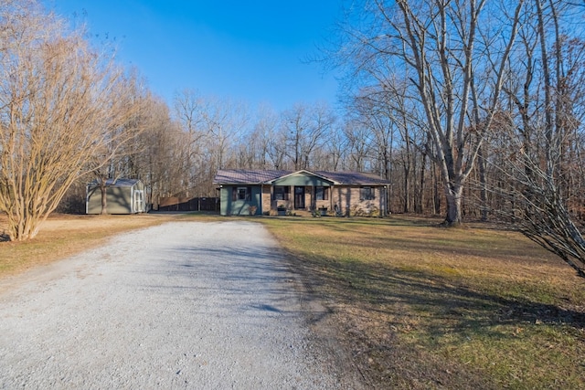 single story home featuring covered porch, a shed, and a front yard