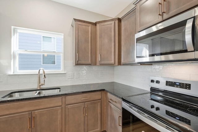 kitchen with stainless steel appliances, tasteful backsplash, dark stone countertops, and sink