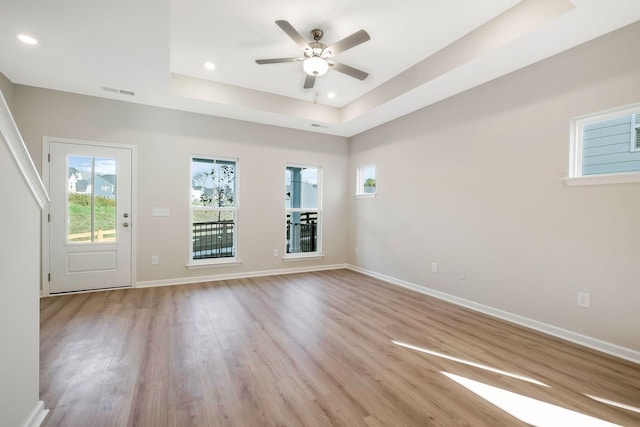 unfurnished room with ceiling fan, a raised ceiling, and light wood-type flooring