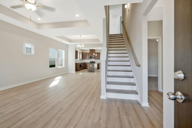 interior space featuring a tray ceiling, hardwood / wood-style floors, and ceiling fan with notable chandelier