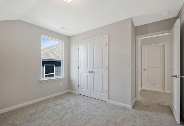 unfurnished bedroom with light carpet, a closet, and lofted ceiling