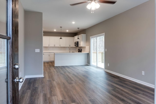 kitchen featuring tasteful backsplash, dark hardwood / wood-style floors, kitchen peninsula, decorative light fixtures, and white cabinets