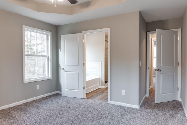 unfurnished bedroom featuring a raised ceiling, light carpet, and ceiling fan